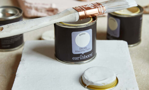 Product shot of Pebble with sample pot and paint brush. Perfect paint for listed buildings