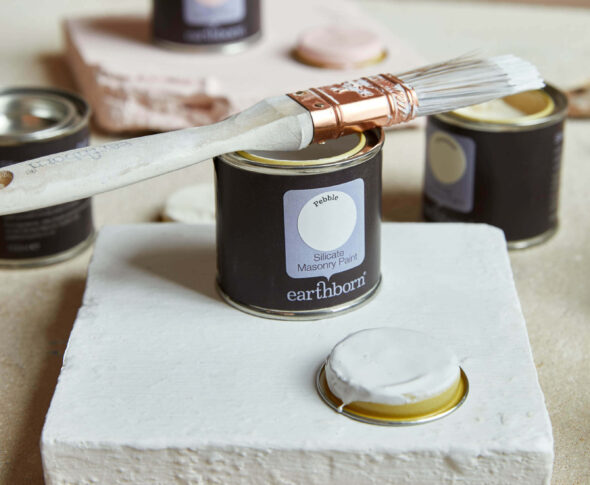 Product shot of Pebble with sample pot and paint brush. Perfect paint for listed buildings