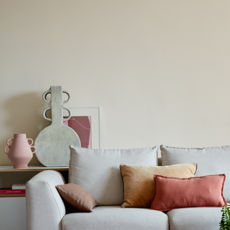 A couch against a wall with throw cushions and decorative vases and framed art.