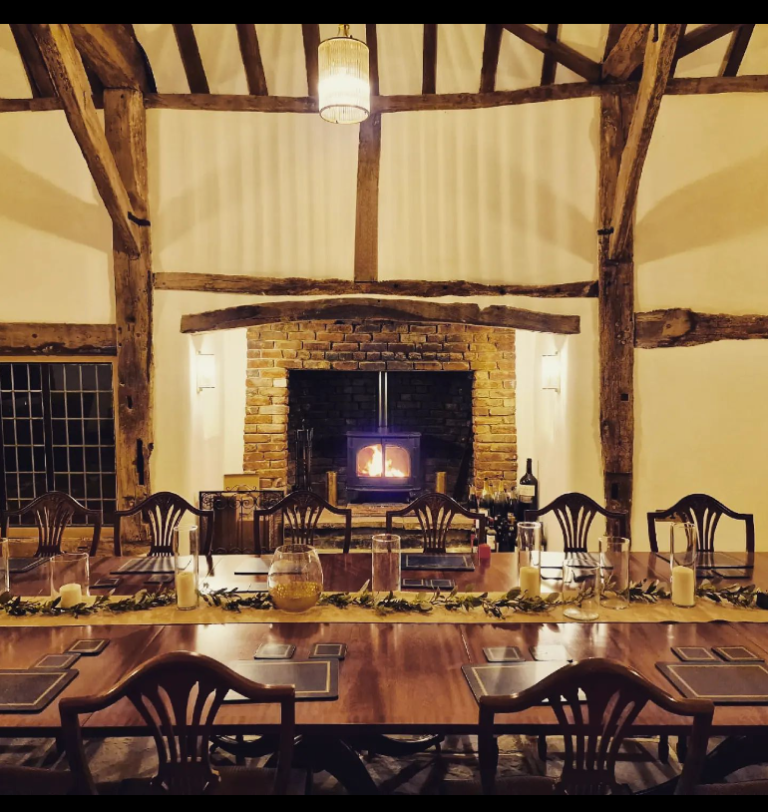 Long dinning room table set for dinner with a fireplace in the background.