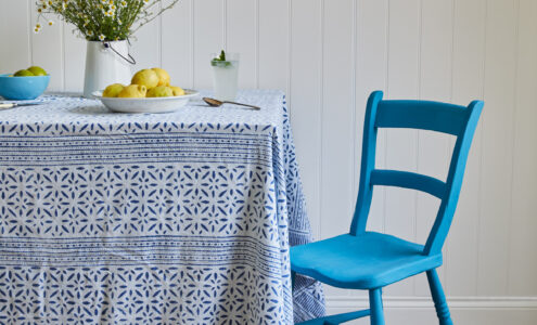 A blue painted chair in front of a white wall