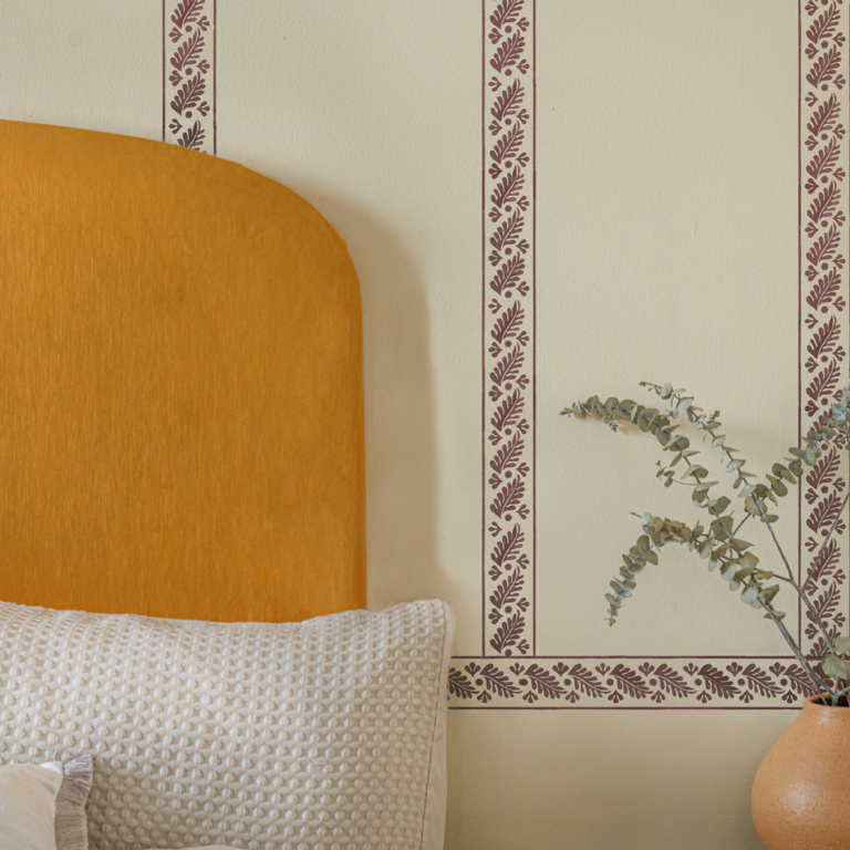 Painted stamp print on a wall adding boarders to a plain wall behind a headboard.