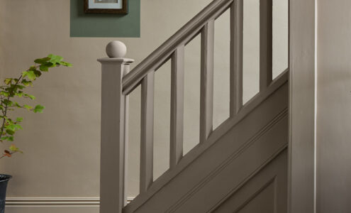 A patterned floor with a short banister leading upstairs. Colour blocking painted on the walls to add to the art hanging.