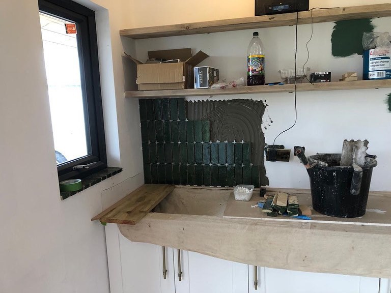 Stripped back and tiling of a wall above cupboards.