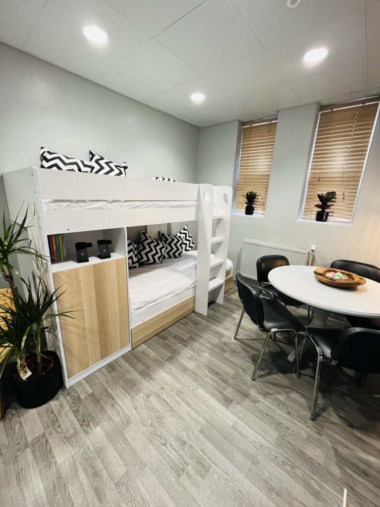 Open plan apartment showing a bunk bed and dinning room table.