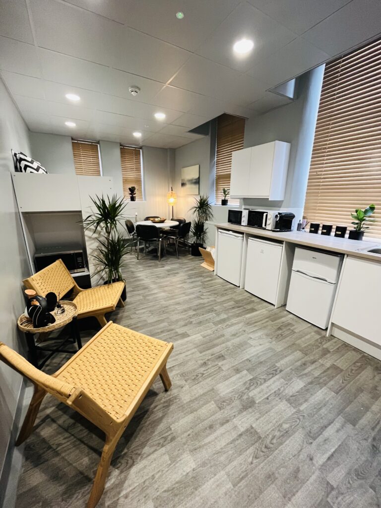 Open plan apartment with a bed, wooden chairs and a dinning room table.