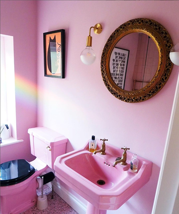 Pink bathroom with gold accents and mirror.
