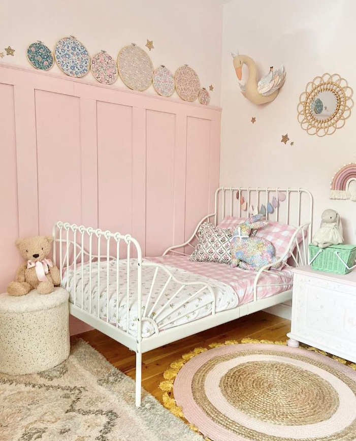 Little girls bedroom with pale pink decorations and soft toys.