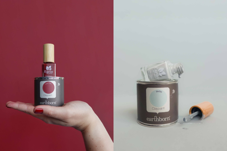 Handing holding Earthborn paint tin with Ruby Red Earthy Nail Polish bottle sitting on top. Grey Nail Polish bottle dripping down a paint tin.